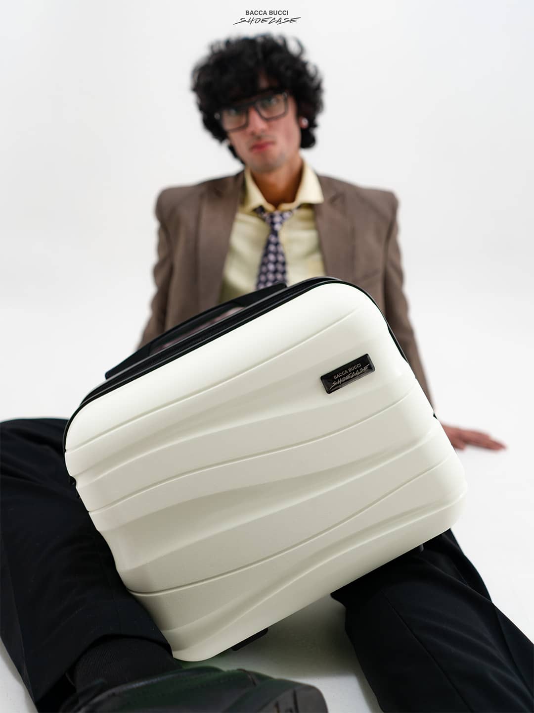 Person holding a white shoecase with a bacca bucci logo on a plain background.